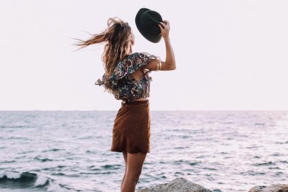 stylish female standing against ocean in windy day